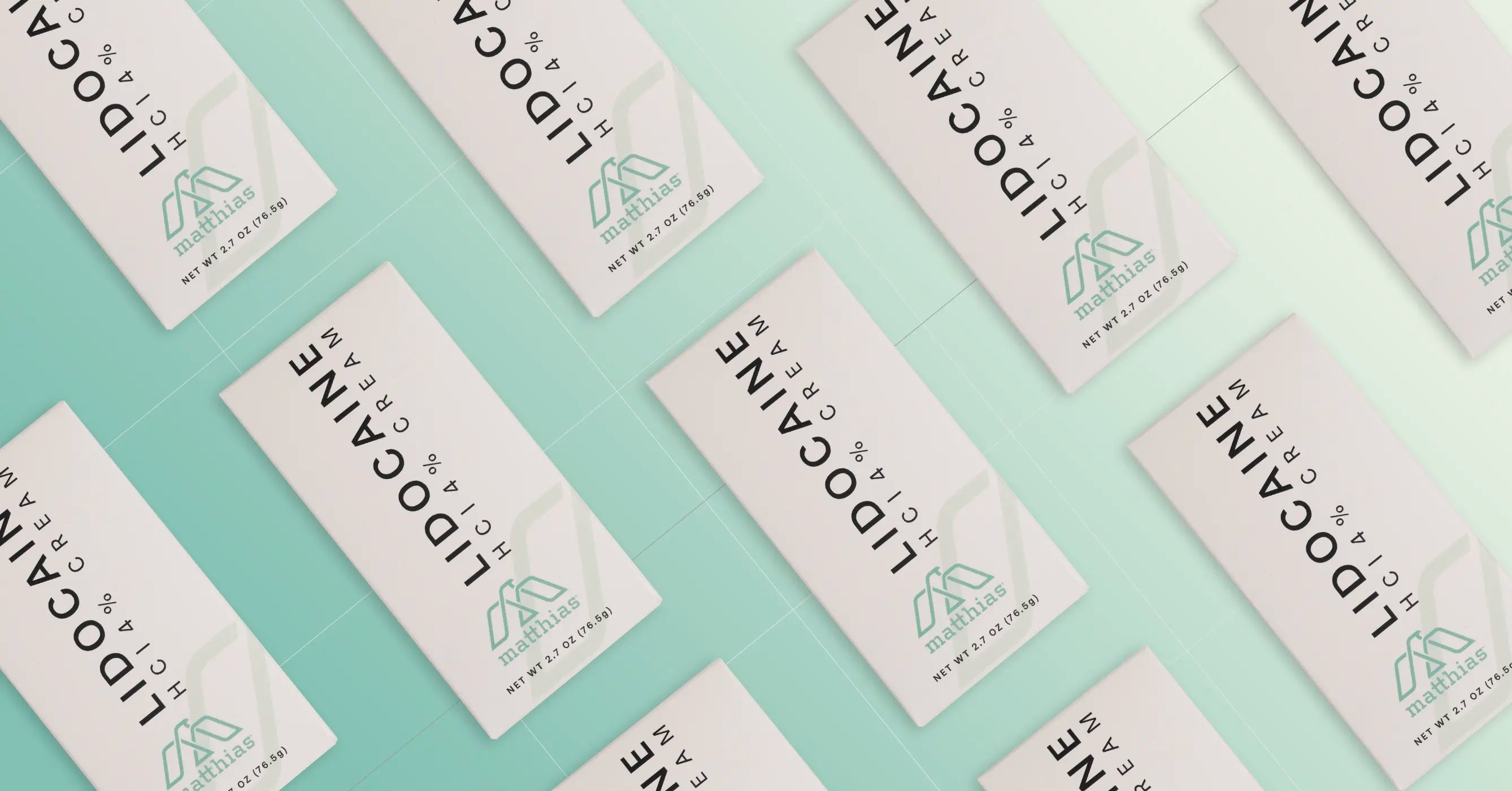 Overhead view of multiple Matthias Lidocaine HCl 4% Cream boxes arranged diagonally in rows on a mint green surface, showing white packaging with black text and teal Matthias logo.